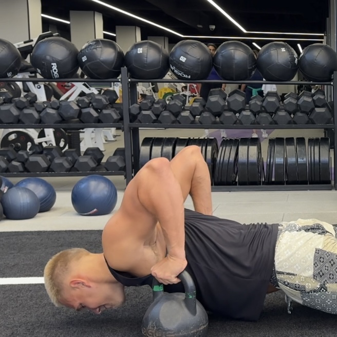 Swimmer demonstrating a shoulder mobility stretch with a kettlebell